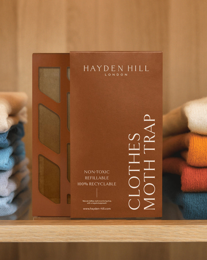 a Hayden Hill Clothes Moth Trap sitting on a shelf between piles of sweaters