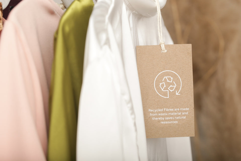 some sustainable silk clothing hanging together with a recycling label attached to them