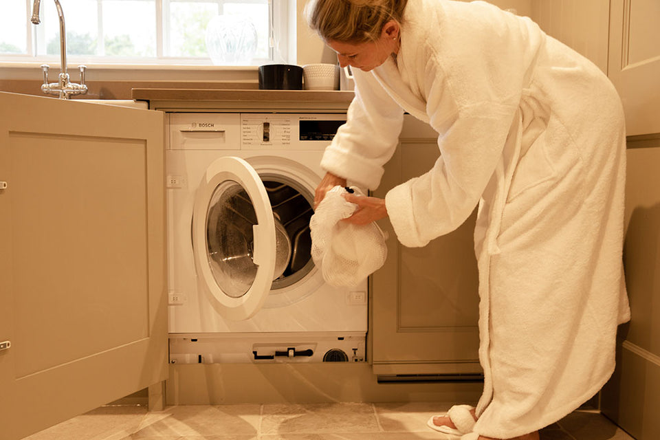 a mesh bag of laundry being put in the washing machine