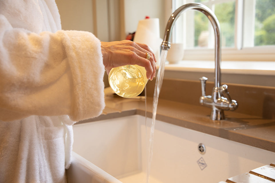 liquid laundry detergent being poured into a basin