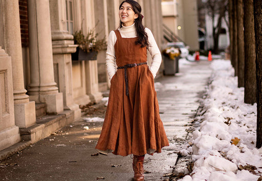 Mai strolling in a snowy street in a russet colored pinafore dress and lace up boots