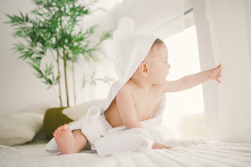 a baby wrapped in a white bamboo hooded towel