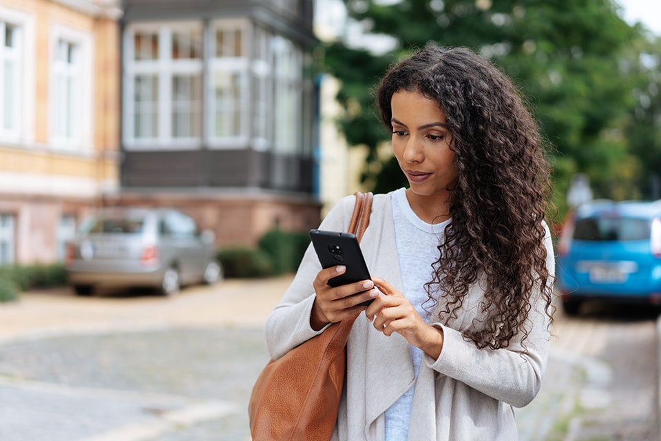 a beautiful woman holding her cell phone which is wrapped in a plastic-free case