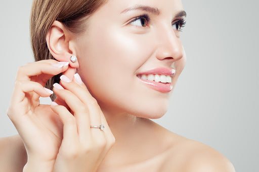a beautiful woman putting on her diamond earrings