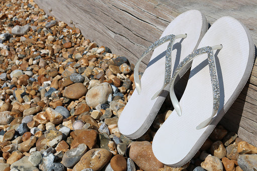 a close up of a pair of white flip-flops with glitter toe posts
