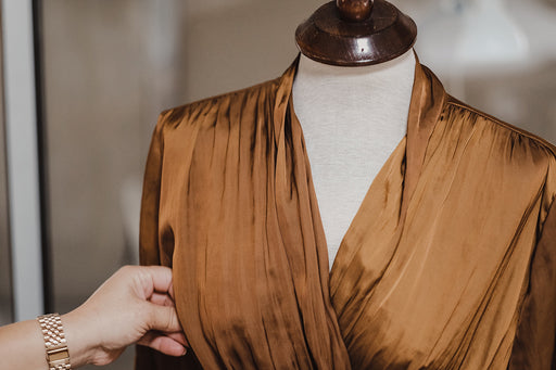 a close up of a pleated silk-looking blouse on a tailor’s mannequin