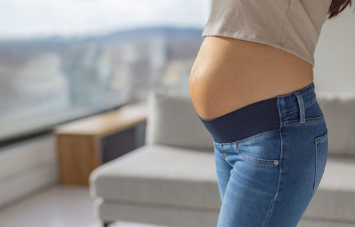 a close up of a pregnant woman wearing maternity jeans