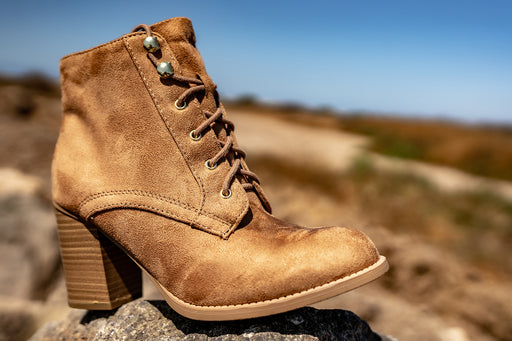 a close up of a tan suede heeled lace up boot