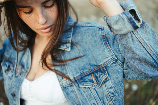 a close up of a woman wearing a summer dress and denim jacket with the sleeves rolled up