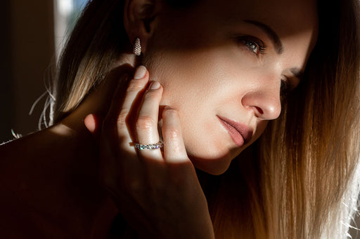 a close up of a woman wearing diamond studded earrings and a diamond ring