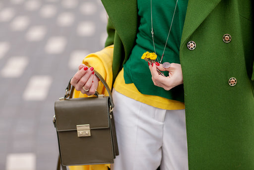 a close up of a woman wearing green and yellow clothing with an olive colored purse