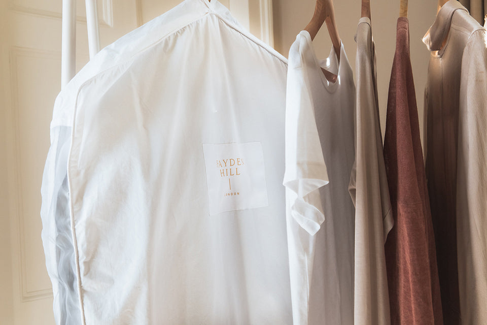 a clothes rail with clothing and a 100% organic cotton Hayden Hill Garment Bag