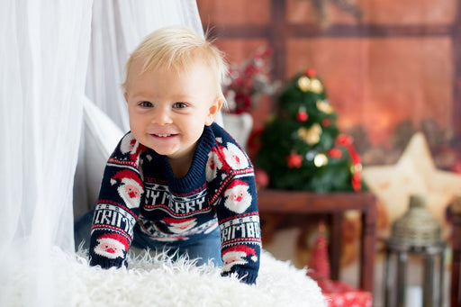 a cute toddler dressed in a ‘Merry Christmas’ sweater
