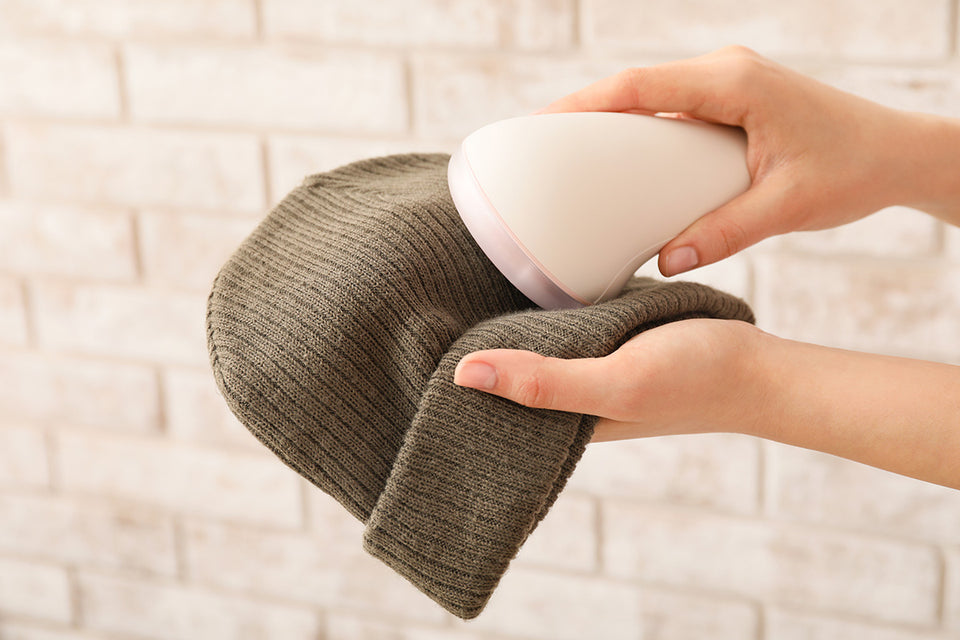 a fabric shaver being used on a woolen beanie
