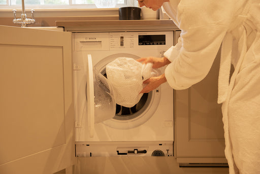 a mesh laundry bag being placed in the washing machine