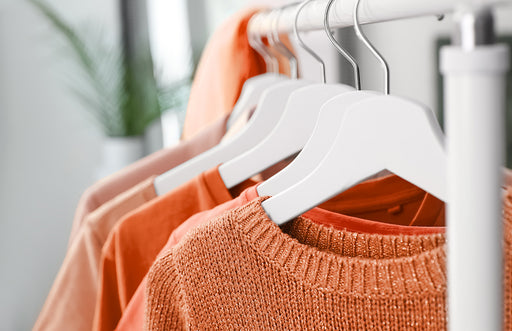  a mixture of different shades of orange colored clothes on hangers