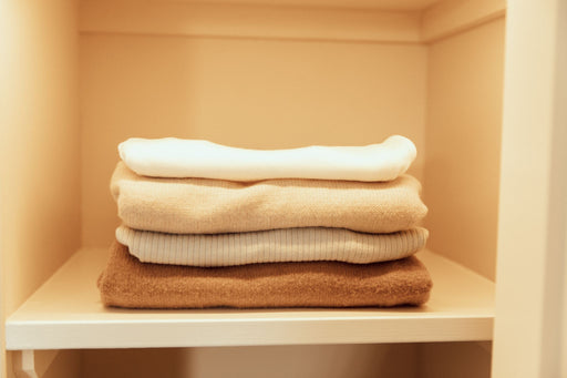 a neat pile of woolens on a closet shelf