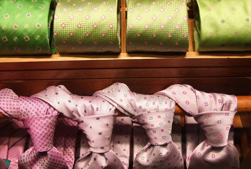 a row of green patterned ties above a row of pink patterned knotted ties