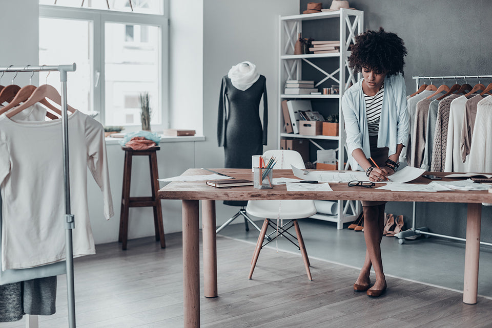 a tailor working on drawings in her studio