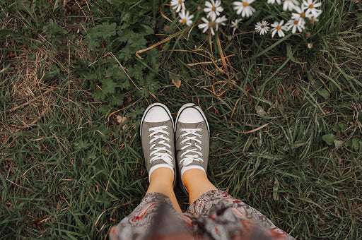 a view looking down on a print skirt and sneakers standing in a field
