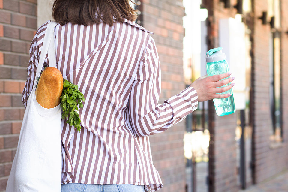 a woman carrying her groceries and a reusable water bottle