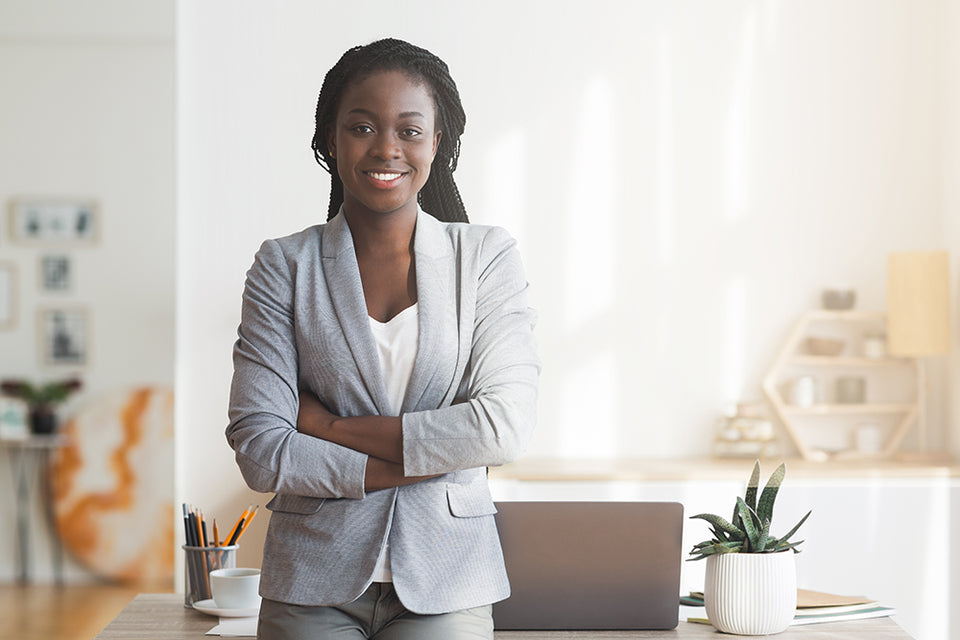 a woman in her office wearing a pale gray jacket, t-shirt and pants