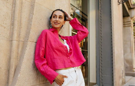 a woman in her thirties wearing cream pants and a fuschia pink shirt