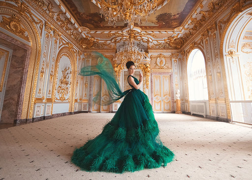 a woman in palatial surroundings wearing a stunning green dress with layers of green feathers