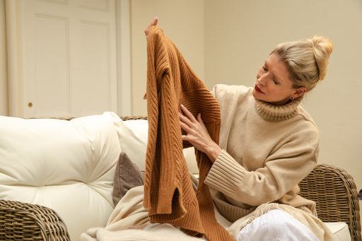 a woman inspecting her rust-colored woolen sweater