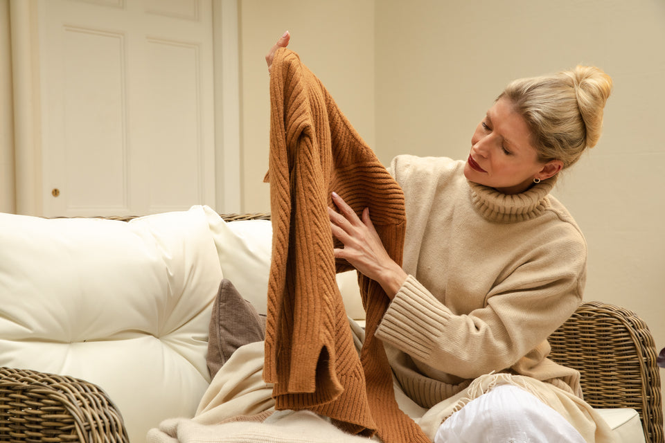 a woman inspecting her rust-colored woolen sweater