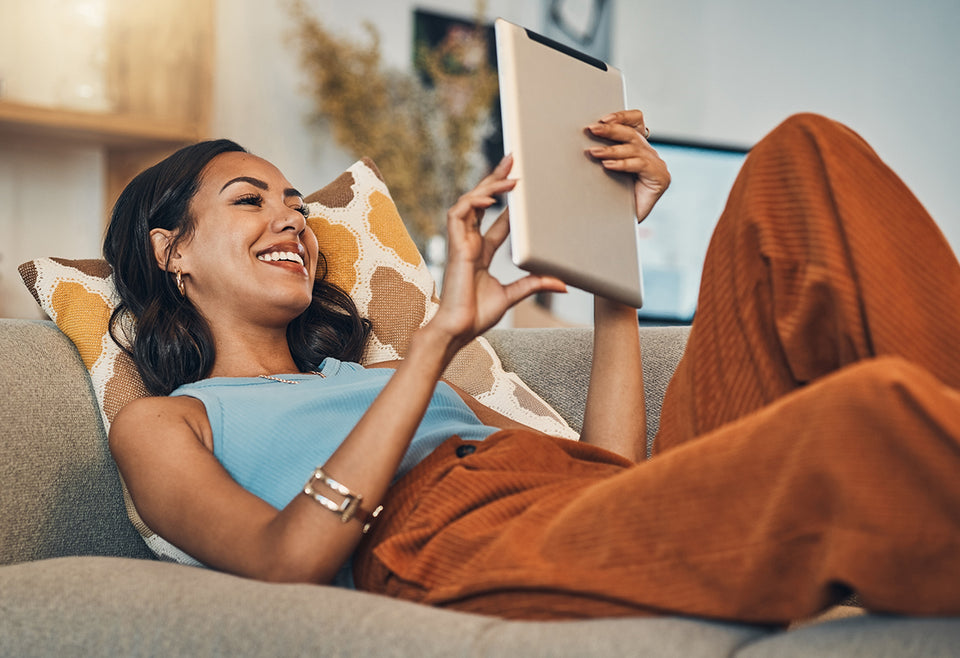 a woman relaxing at home watching a movie on her tablet
