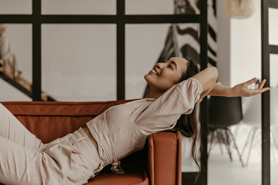 a woman relaxing on her couch in a beige short wrap top and high waisted beige pants