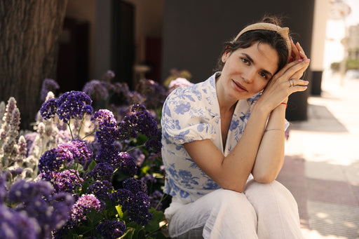 a woman sitting down wearing a blue floral patterned short sleeve top