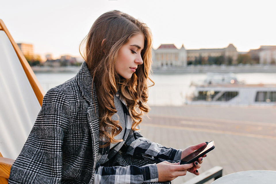 a woman sitting outdoors in a black and white check shirt paired with a tweed black and white overcoat