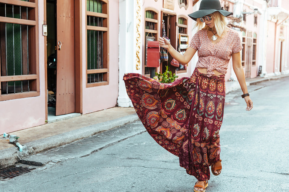 a woman wearing a boho style printed top and long skirt