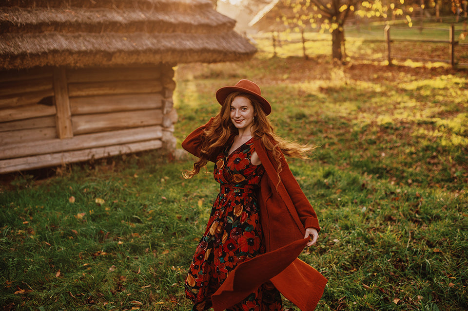 a woman wearing a brightly coloured dress under a rust-colored woolen long cardigan