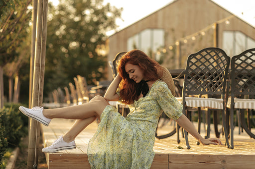 a woman wearing a flowery boho dress paired with white sneakers