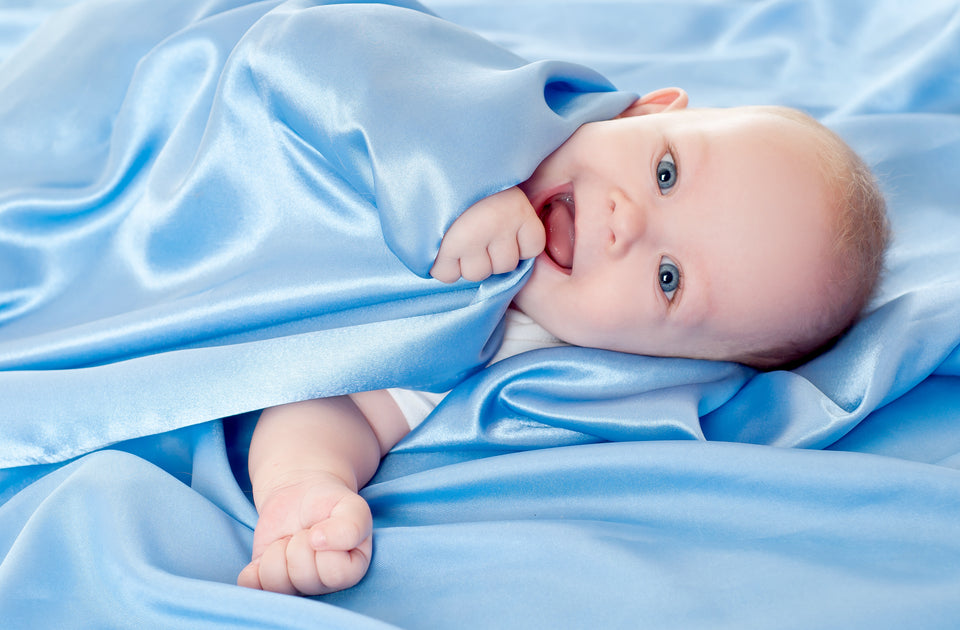 a gorgeous baby with bright blue eyes lying on pale blue silk