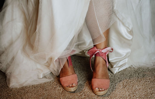 beautiful dusty pink wedge sandals with ribbon ties being worn with a wedding dress