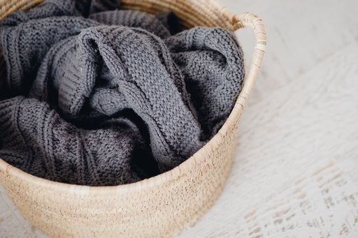 a dark gray woolen blanket in a wicker laundry basket