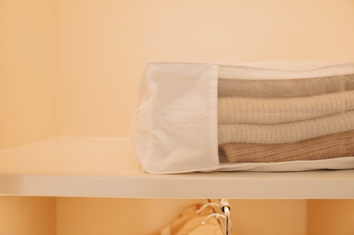 a pile of cashmere sweaters inside a zippered storage bag by Hayden Hill