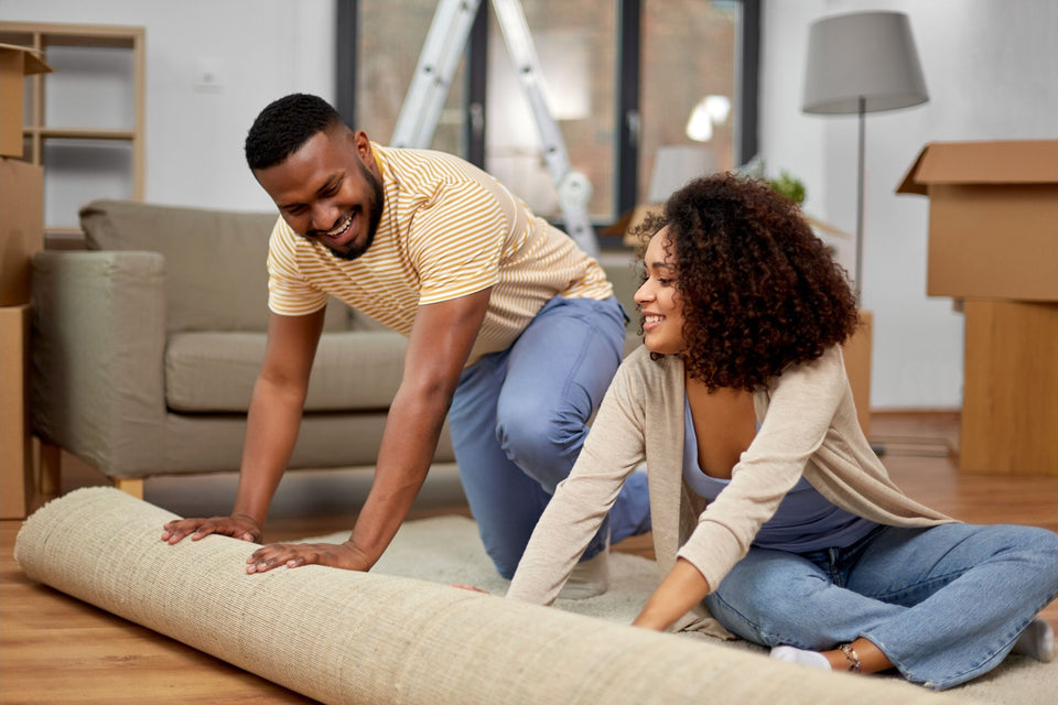 a couple rolling out a carpet in their new home