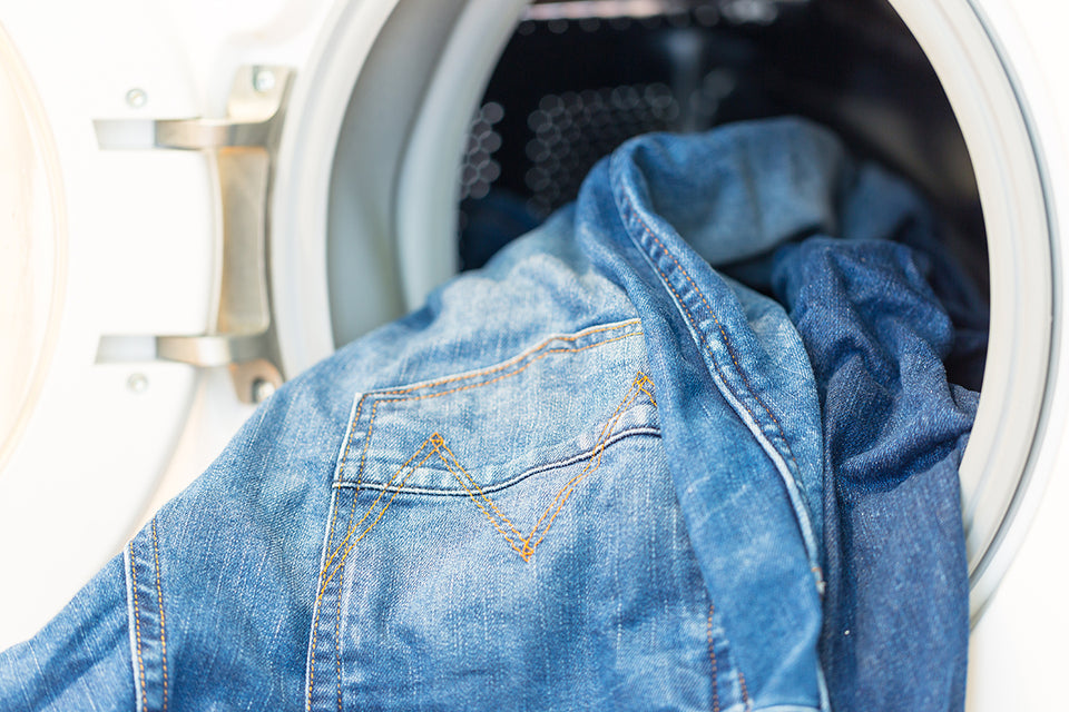 denim clothing being put into the washing machine