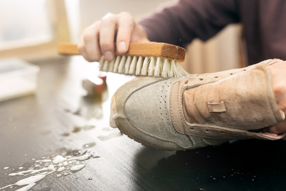 a pair of sneakers being cleaned with a brush
