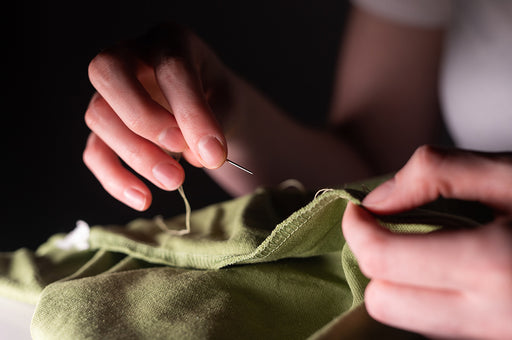 hands stitching some green fabric