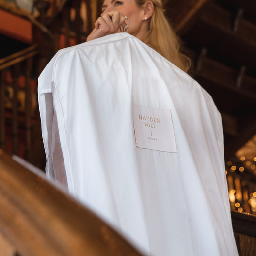 a woman carrying a hanging bag on a hanger over her shoulder