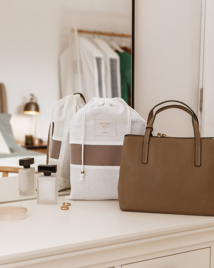 a dust bag on a dressing table next to a brown handbag