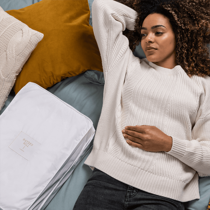 a woman lying on a bed next to a storage bag
