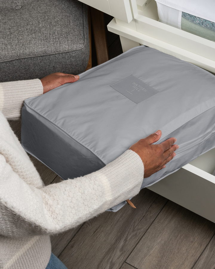 a grey storage bag being placed into a drawer