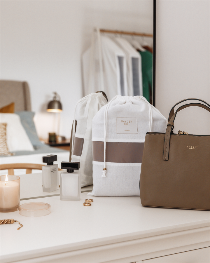 a dust bag on a dressing table next to a brown handbag
